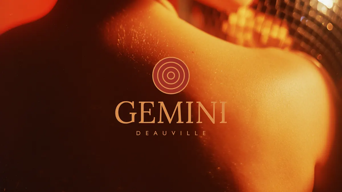 Logo Gemini, cercles concentriques et capitales sérif espacées, sur une épaule nue sous une boule à facettes