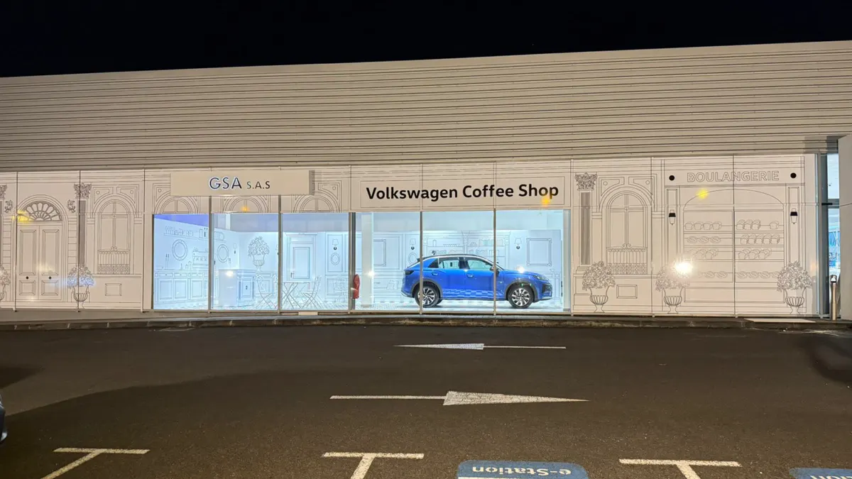 Façade habillée de la concession Volkswagen éclairée de nuit, le T-Roc exposé en vitrine