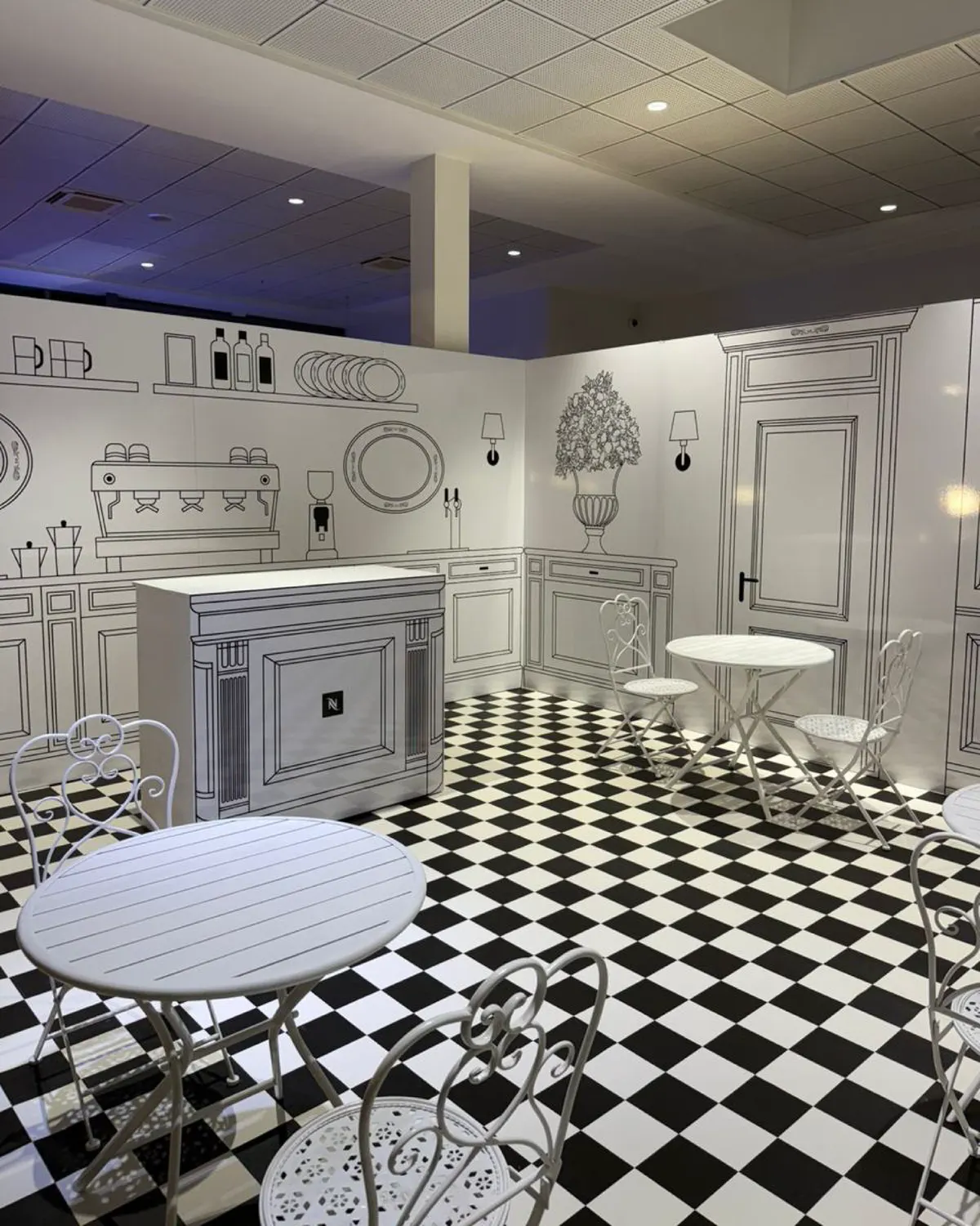 Pop-up à taille humaine reproduisant l'intérieur du coffee shop, sol en damier et mobilier blanc